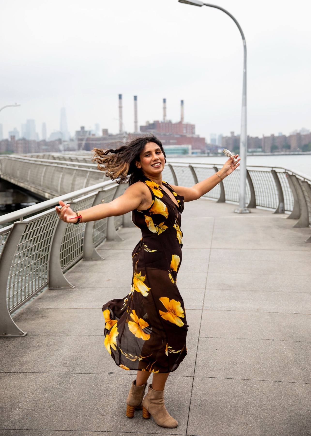 Tanisha dancing on a waterfront walkway, the city skyline behind her