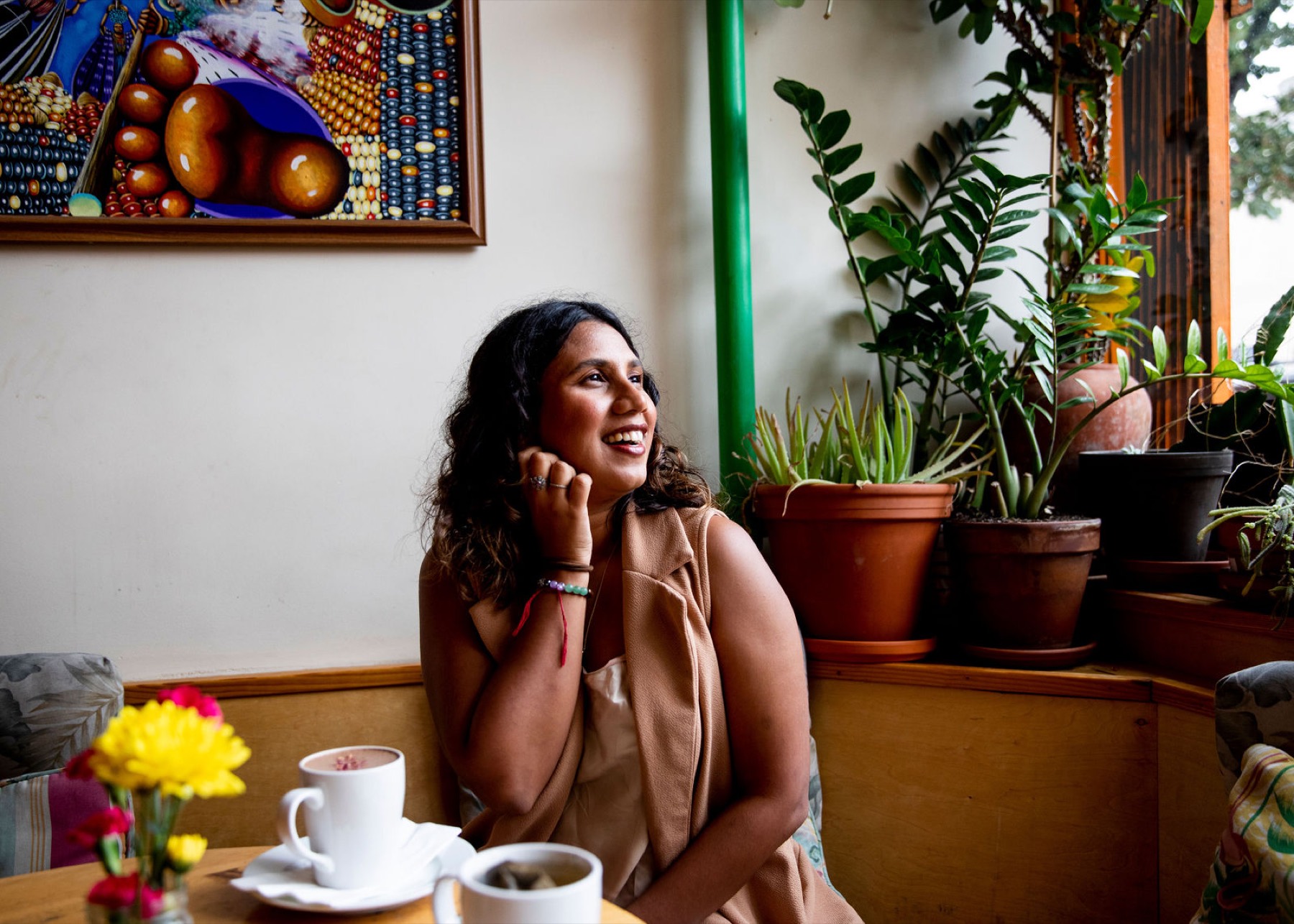 Tanisha seated quietly on a couch, gaze soft, morning light on the plants